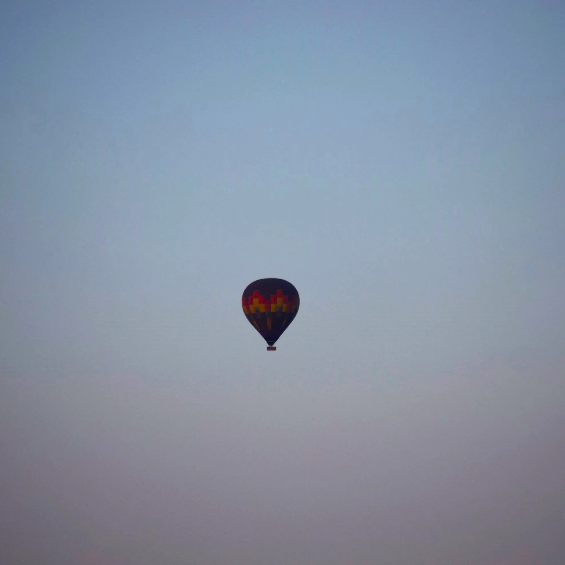 A lone hot air balloon silhouetted against the early morning sky