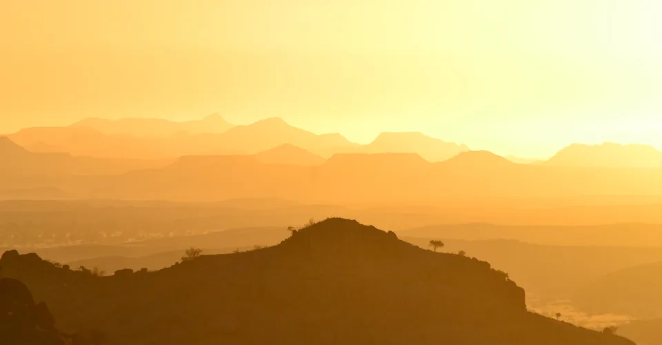 Mountain ranges bathed in warm golden light at sunset over the Namibian landscape